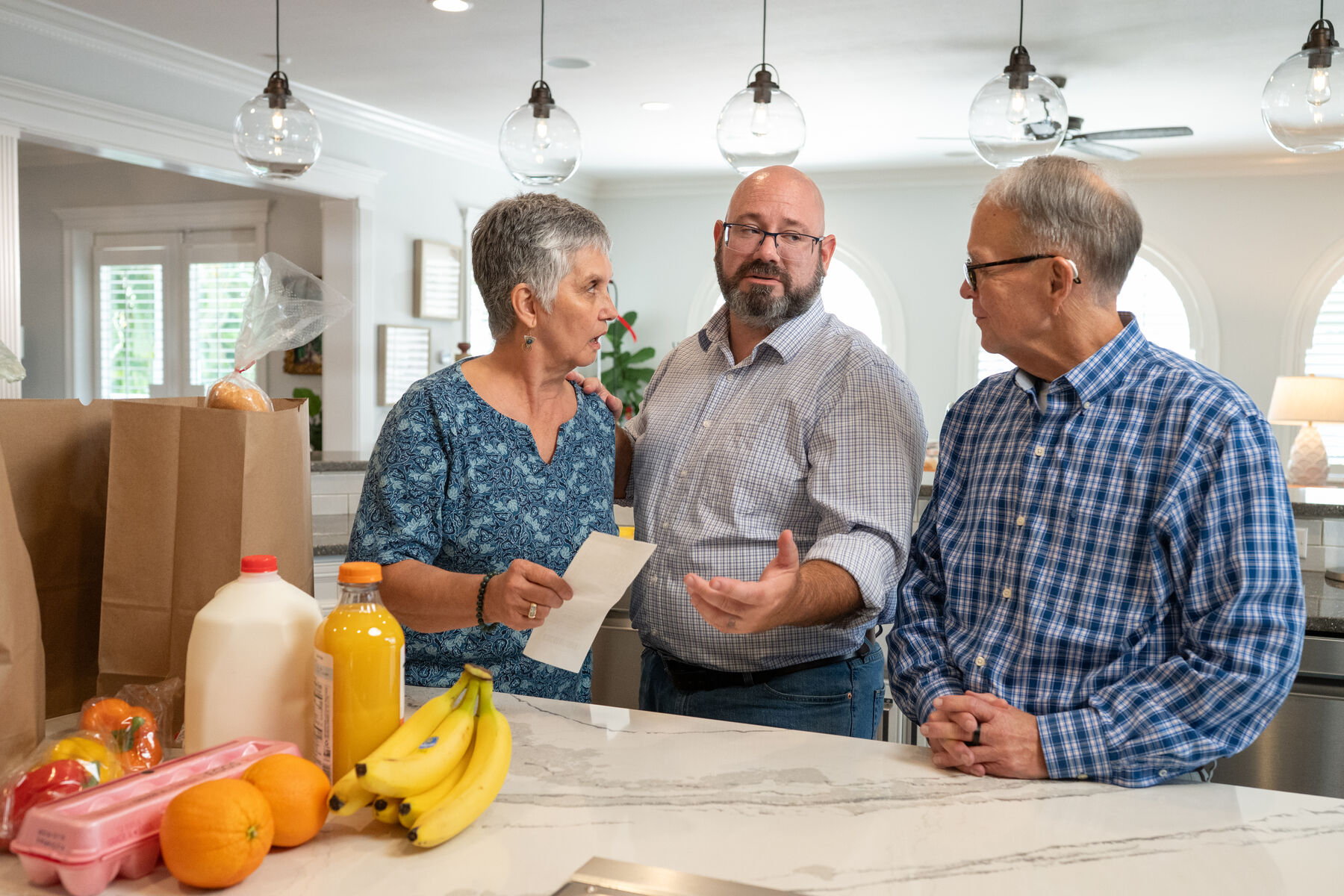 Brian Nathan talking with two Tampa residents in a kitchen about the cost of groceries